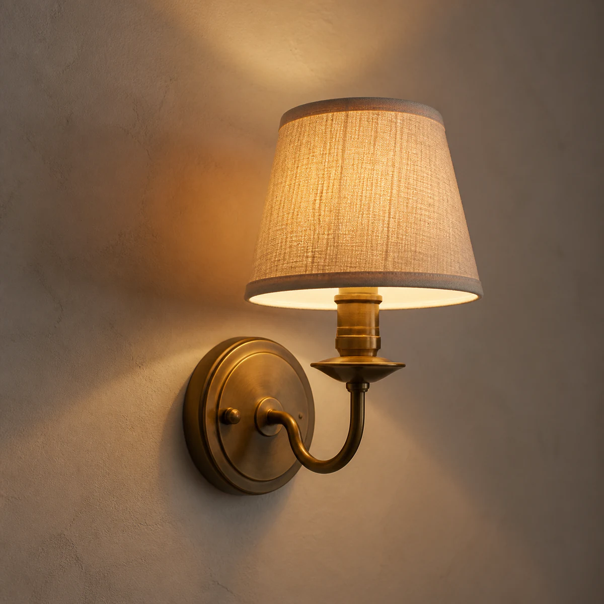 A brass wall light with a linen shade from our range